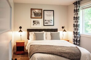 Un dormitorio con cama, dos mesitas de noche y una ventana con cortinas.