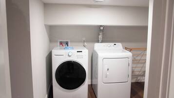 A laundry room with two white washing machines and a drying rack.