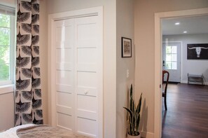A room with a white door, a plant, and a framed picture on the wall.