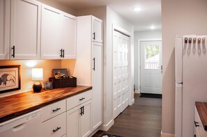 Una cocina con armarios blancos, encimera de madera y refrigerador.