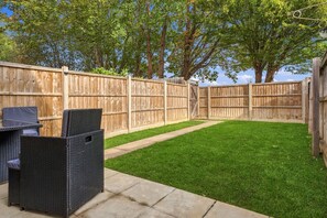 A backyard with a wooden fence, a grassy lawn, and outdoor furniture. - Cambridge home with parking & garden (Cambridge)