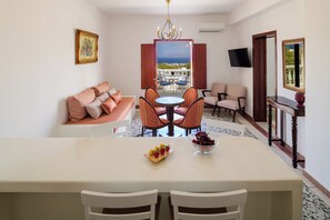 A dining area with a table, chairs, and a bowl of fruit. - One Bedroom Villa with Sea View, Kaminia Holiday Homes (Thira - Santorini)