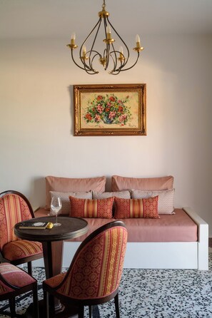 A room with a sofa, patterned cushions, a round table with a glass, and a chandelier. - One Bedroom Villa with Sea View, Kaminia Holiday Homes (Thira - Santorini)