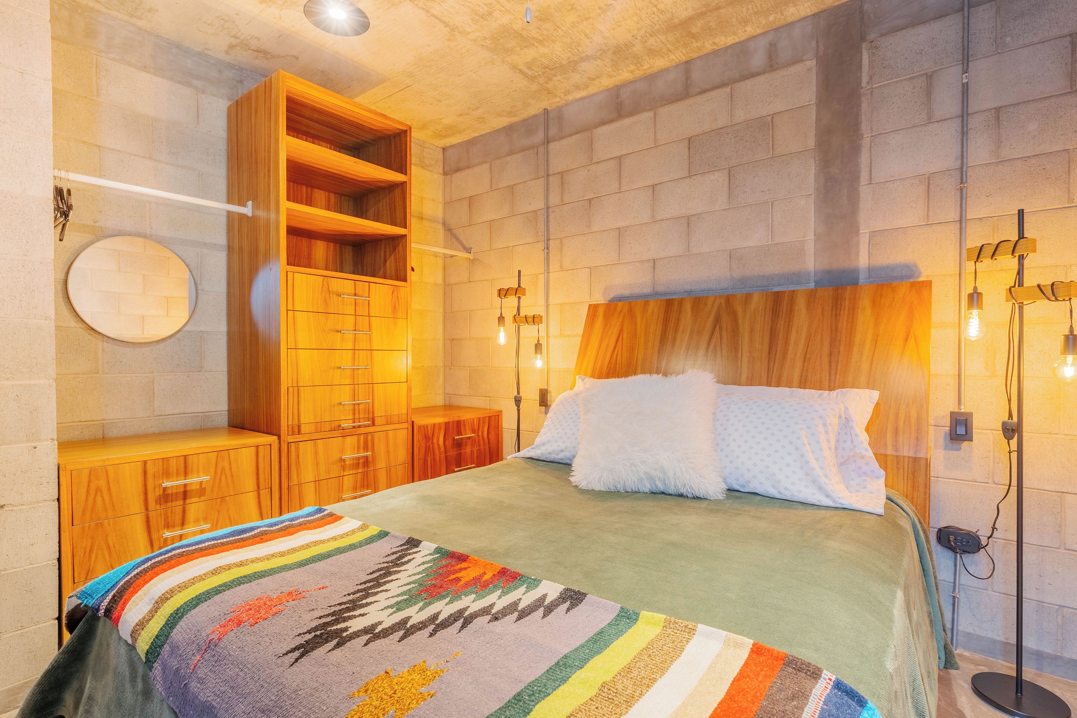 Ein Schlafzimmer mit einem Bett, einem Holzschrank, einem runden Spiegel und Wandleuchten.