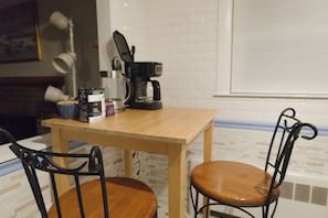A dining area with a wooden table and two chairs, a coffee maker, and a bowl of cereal on the table. - Spacious 3-Bedroom House in Boston with Free Parking (Boston)
