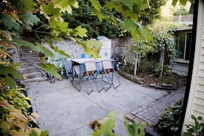 A patio area with a table and chairs, a stone wall, and a garden with various plants. - Spacious 3-Bedroom House in Boston with Free Parking (Boston)