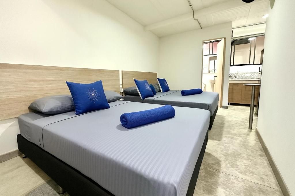 Quarto de hotel com duas camas, uma cozinha compacta e um banheiro.
