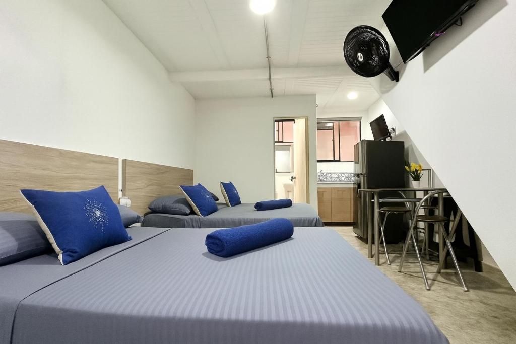 Une chambre d’hôtel avec deux lits, un bureau, une chaise, une télévision et une kitchenette.