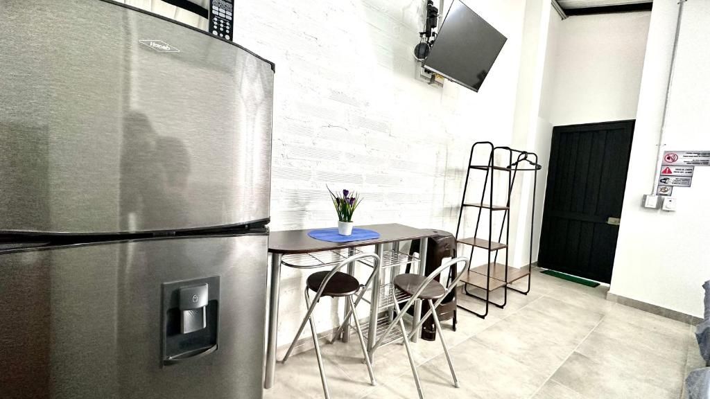A kitchen with a stainless steel refrigerator, a small table with two chairs, and a wall-mounted TV.