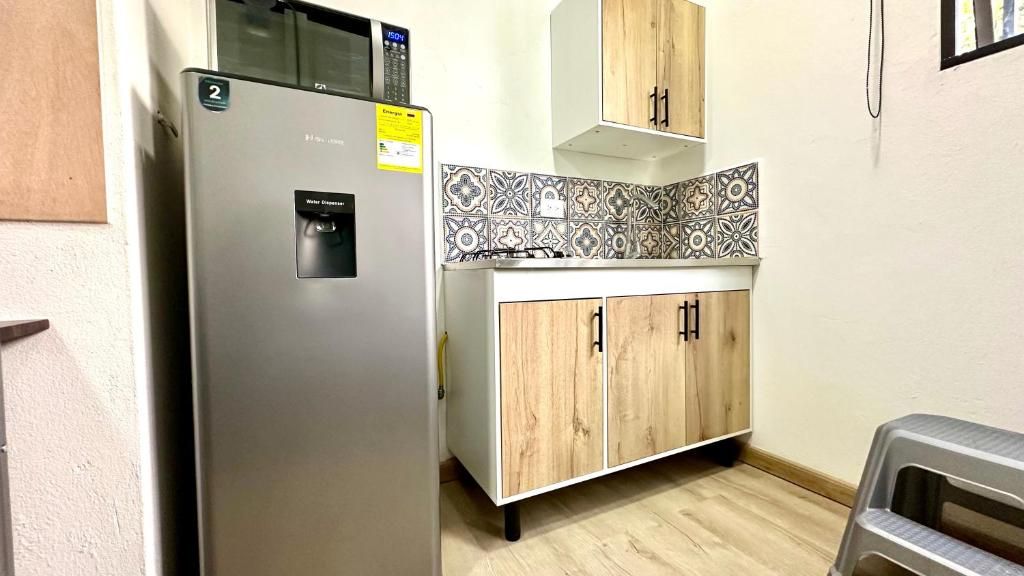 A compact kitchen with a refrigerator, wooden cabinets, and a tiled backsplash.