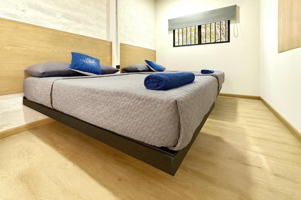 Uma cama moderna com cabeceira, uma janela com vista e uma mesa de cabeceira com abajur.