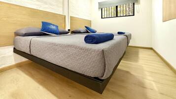 Uma cama moderna com cabeceira, uma janela com vista e uma mesa de cabeceira com abajur.