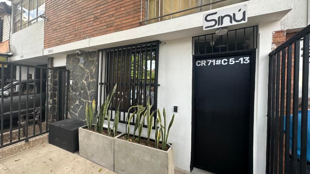 Un edificio con una puerta negra identificada con 'CR 71#C 5-13' y un letrero encima.