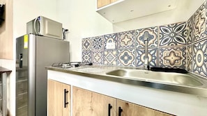 A kitchen with a stainless steel refrigerator, a sink, and patterned backsplash tiles. - Sinu Loft (Medellín)