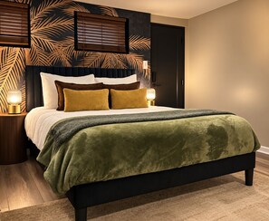 Ein Bett mit grüner Decke, einem Holzkopfende und zwei Nachttischlampen.