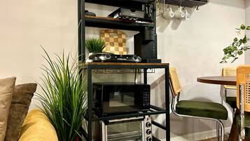 A kitchenette with a built-in oven, a coffee machine, and a shelf with kitchenware.