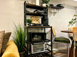 Eine Küchenzeile mit Backofen, einer Kaffeemaschine und einem Regal mit Küchenutensilien.