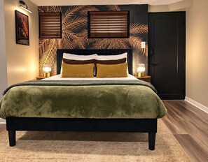 A bed with a green blanket, two bedside lamps, and a wall with a leaf pattern. - Private DC Studio - Free Parking - Lake Trail - Near Navy Yard + Capitol Hill (Washington)