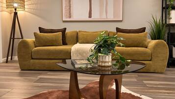 A living room with a sofa, a glass coffee table, a lamp, and a painting on the wall.