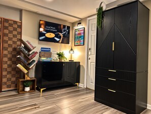 Ein modernes Wohnzimmer mit einer schwarzen Unterhaltungsecke, einem an der Wand montierten Fernseher und einem Bücherregal mit Büchern und Dekoration.
