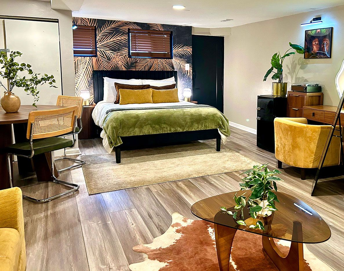 A modern bedroom with a bed, a desk, chairs, and a coffee table.