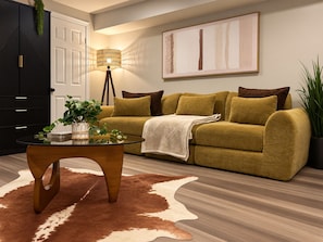 A living room with a sofa, a glass coffee table, a lamp, and a cowhide rug.
