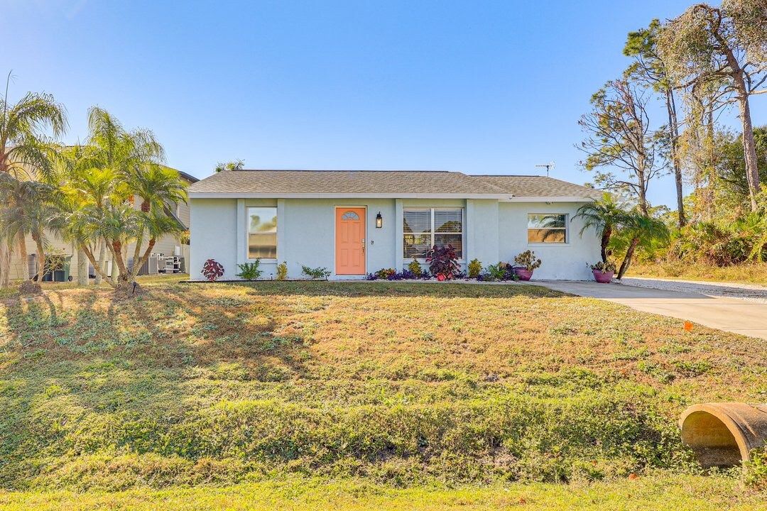 A single-story house with a front porch, a small garden, and a driveway.