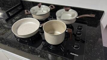 Cozinha com fogão preto, quatro panelas e coifa.