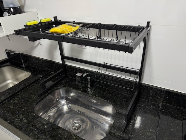 Une cuisine équipée d’un évier à deux bacs, d’un égouttoir noir et d’un évier en acier inoxydable.