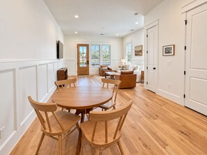 A spacious dining area with a wooden table and chairs, a sofa, and a television mounted on the wall. - Homewood Luxury 2 Bedroom 2 Bath Townhome 3020 (Homewood)