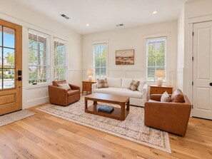 A spacious living room with a wooden floor, a sofa set, a coffee table, and a painting on the wall. - Homewood Luxury 2 Bedroom 2 Bath Townhome 3020 (Homewood)
