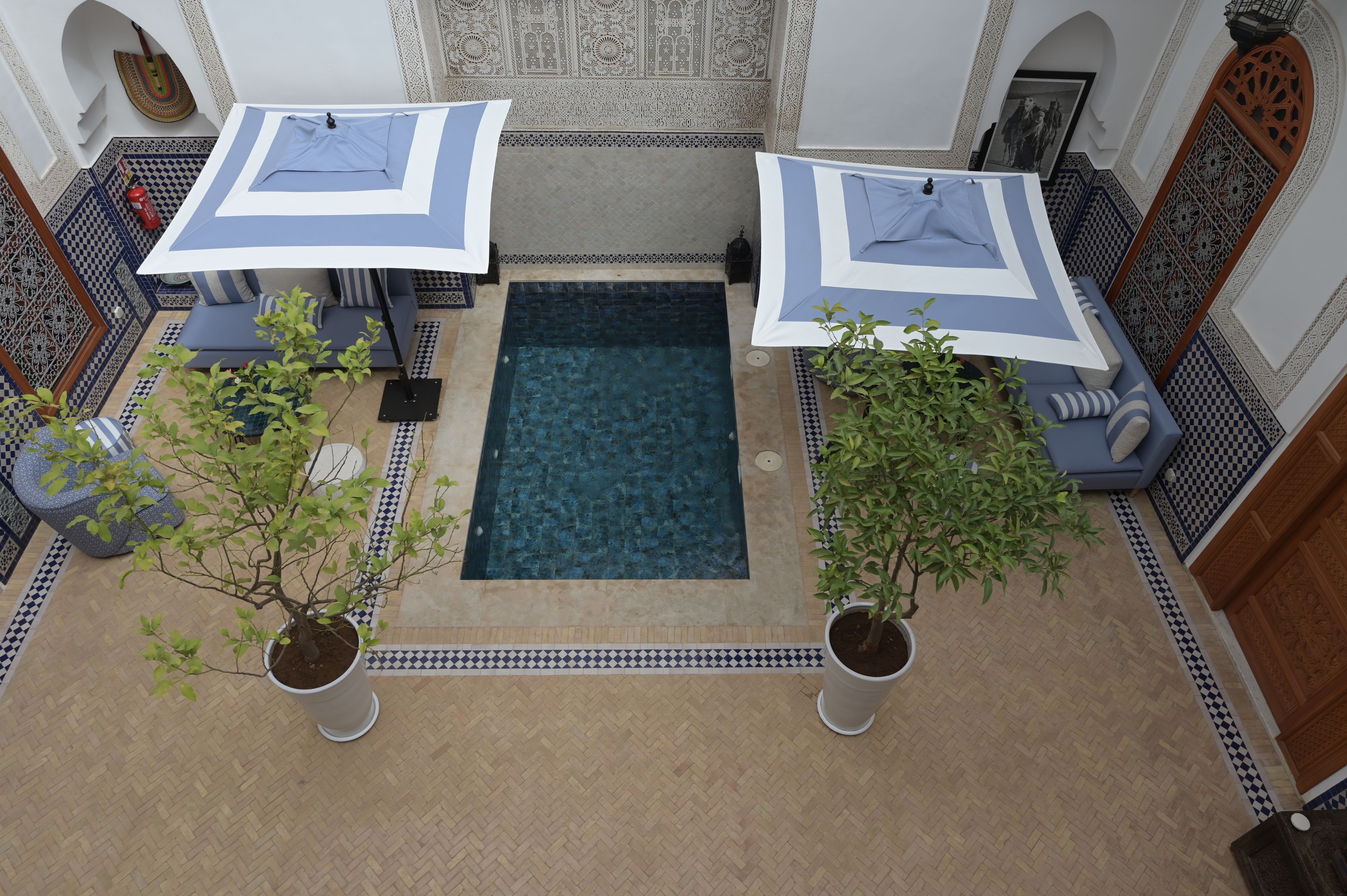 Un espace piscine aménagé sur le toit, avec deux parasols, un canapé et des plantes en pot.