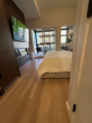 Un dormitorio con cama, televisión y vistas a un balcón.