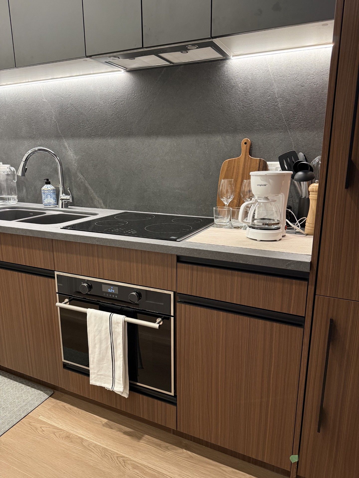 A modern kitchen with a built-in oven, a stainless steel sink, and a coffee maker.