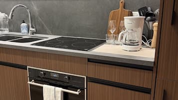 A modern kitchen with a built-in oven, a stainless steel sink, and a coffee maker.
