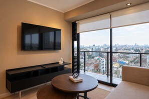 Una sala de estar moderna con un televisor grande, una mesa redonda y un sofá.