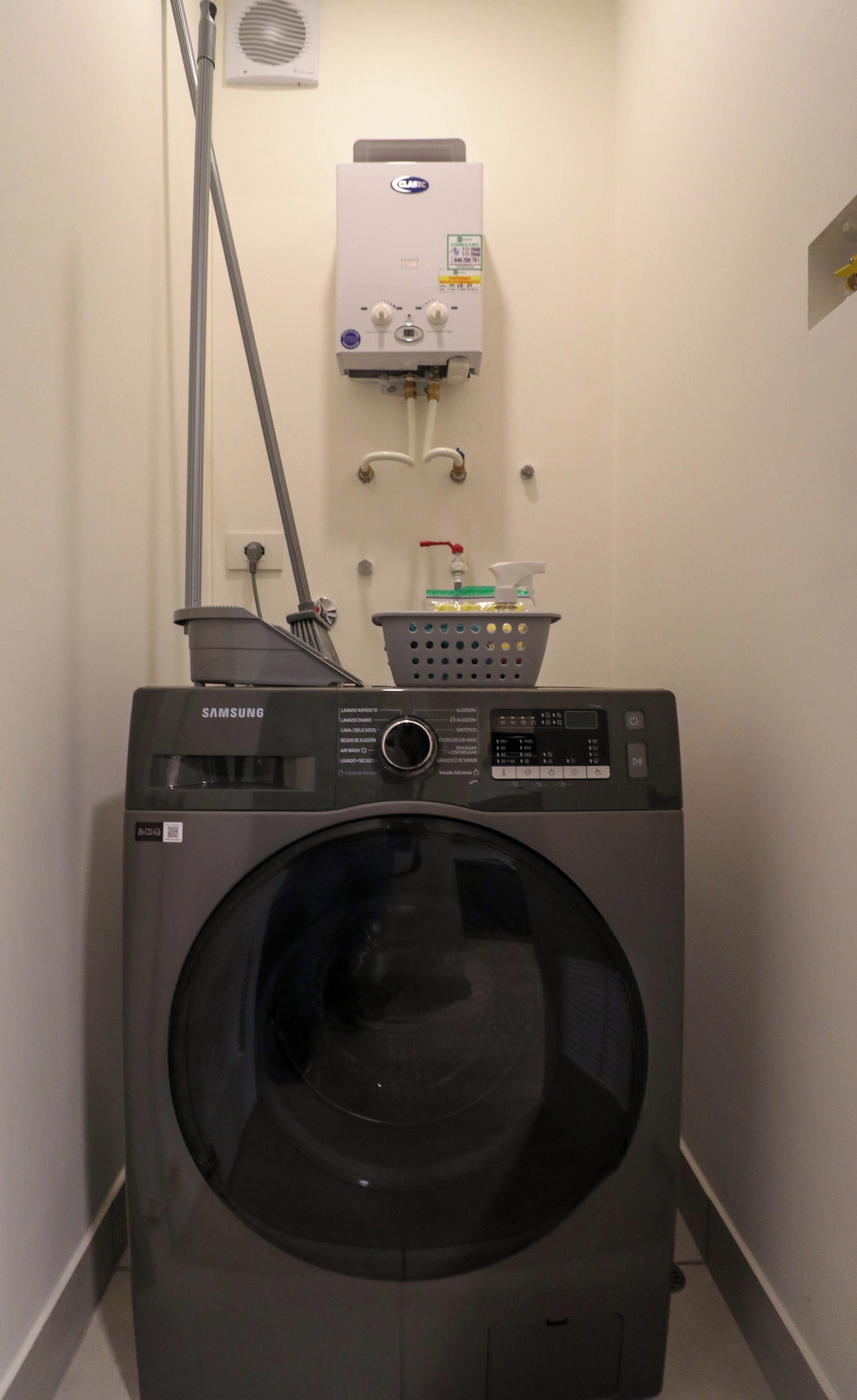 A laundry room with a Samsung washer and dryer, a water heater, and a hose.