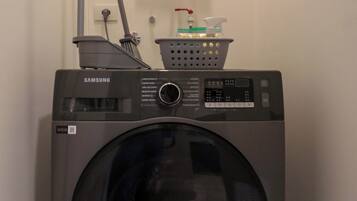 A laundry room with a Samsung washer and dryer, a water heater, and a hose.