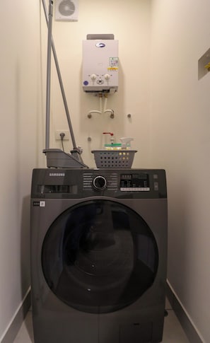 Lavandería con lavadora y secadora Samsung, calentador de agua y una manguera.