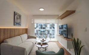 A modern living room with a sofa, a coffee table, and a TV on a stand. - w* | Amazing 2BR w/ Partial Sea View in Miraflores (Miraflores)