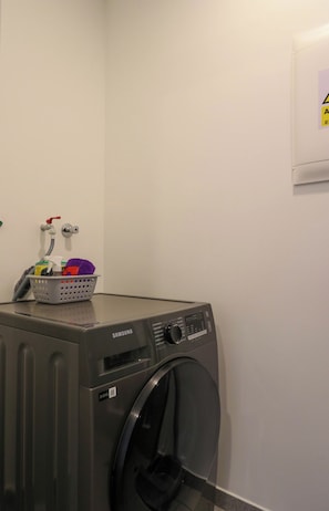 A Samsung front-loading washing machine in a laundry room with a basket of laundry and a faucet on the wall. - w* | Amazing 2BR w/ Partial Sea View in Miraflores (Miraflores)