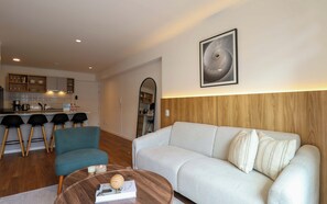 A modern living room with a sofa, a coffee table, and a kitchen area in the background. - w* | Amazing 2BR w/ Partial Sea View in Miraflores (Miraflores)