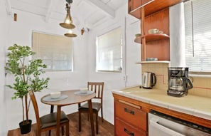 A dining area with a table and chairs, a potted plant, and a coffee maker on the counter. - Rustic Urban Homestay • Pet-friendly (Pomona)