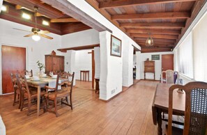 A spacious dining area with wooden flooring, a high ceiling with exposed beams, and a ceiling fan. - Rustic Urban Homestay • Pet-friendly (Pomona)