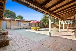 An outdoor patio with a covered area, a table with chairs, and a red umbrella. - Rustic Urban Homestay • Pet-friendly (Pomona)
