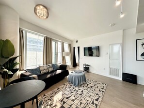 A modern living room with a sofa, a round table, and a patterned rug. - The Modern Retreat | Luxury 2 Bed, 2 Bath Condominium (Mississauga)
