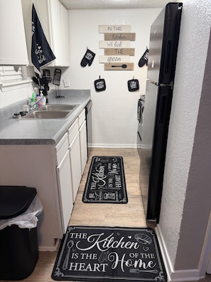 A kitchen with a black and white backsplash, a stainless steel refrigerator, and a wooden floor. -  A cozy stylish 2- story loft with a peaceful vibe (Addison)