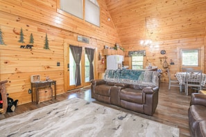 Ein Holzblockhaus-Interieur mit Ledersofa, Esstisch und Küchenzeile.