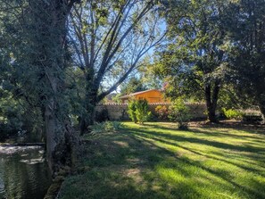 A residential property with a stone wall, a grassy lawn, and a building with a red roof. - The Echo of the Rut - BOUZANCOURT (BOUZANCOURT)