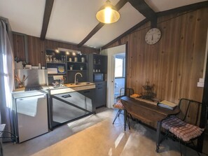 A compact kitchen with a built-in refrigerator, a sink, and a dining area with a wooden table and chairs. - The Echo of the Rut - BOUZANCOURT (BOUZANCOURT)